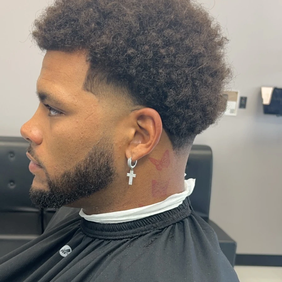 Full side profile showing a textured haircut, tapered sides, and sharply shaped beard